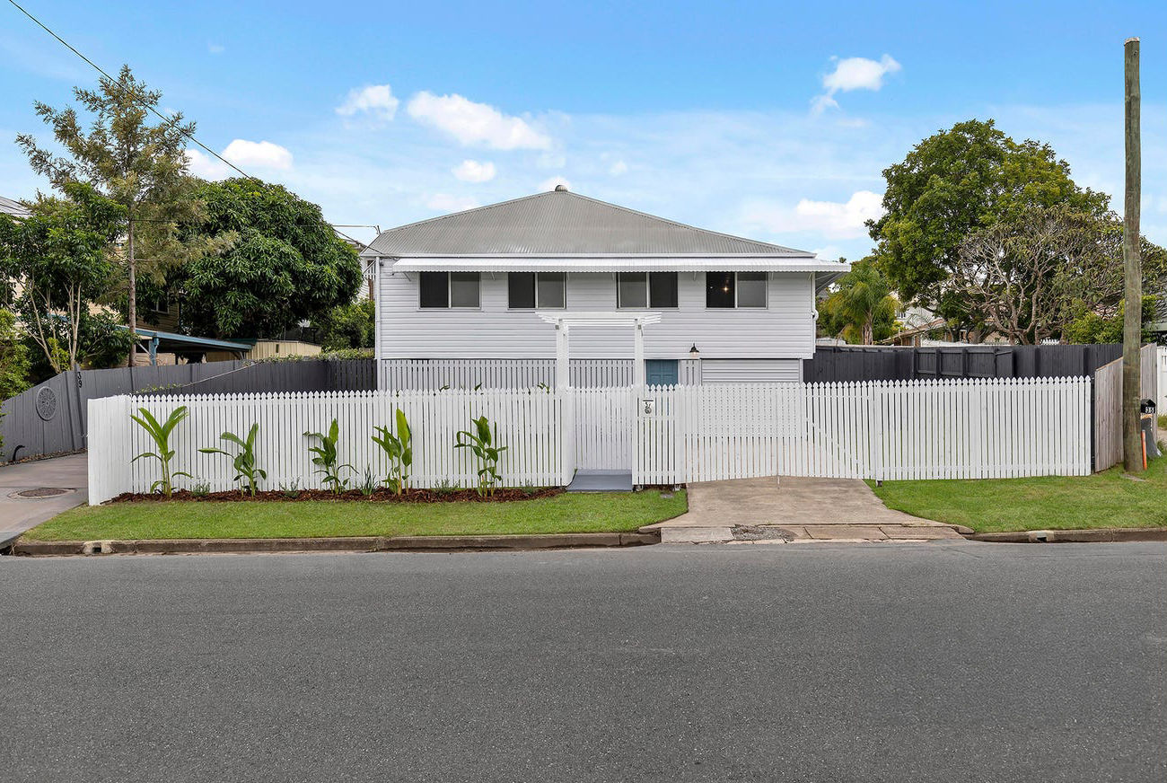 Renovated Queenslander home behind a new white picket fence, Brisbane